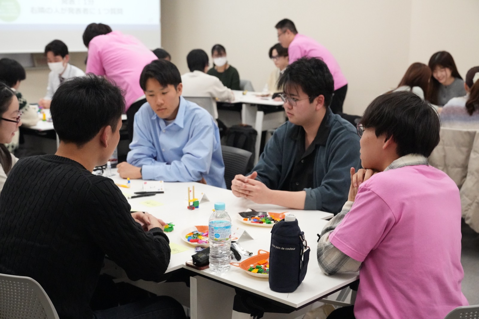 チームでテーブルを囲み課題に取り組む学生